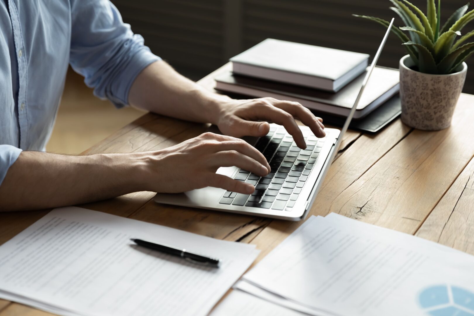 Someone writing a blog article on a laptop with notes and books around
