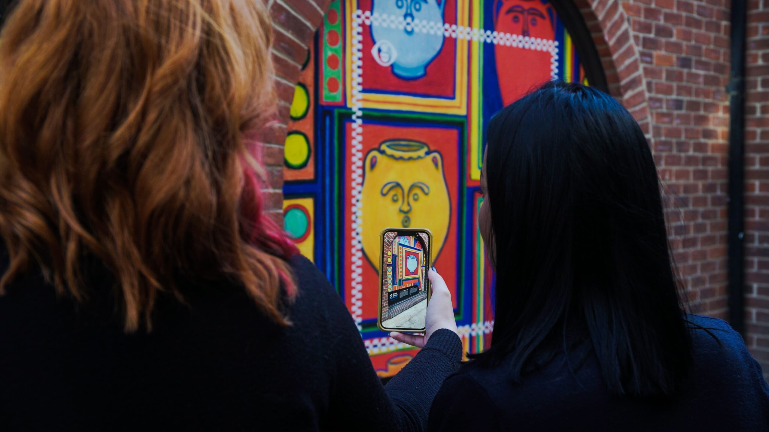 two women looking at an art installation in Colchester through an AR app
