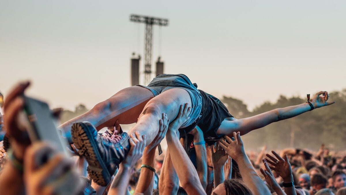 The audence carry the young woman on their hands during rock concert