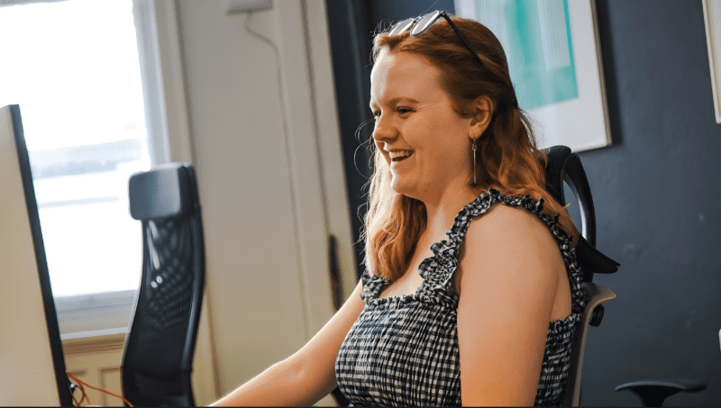 Designer, Charly, smiling at her desk